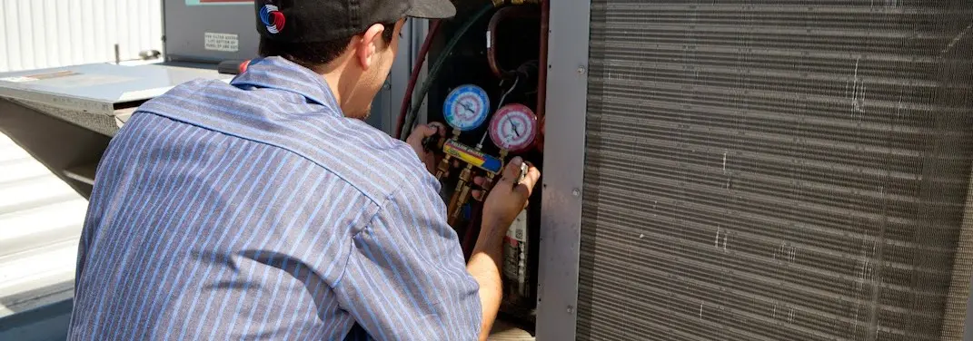 HVAC technician servicing a condenser unit in Belvedere